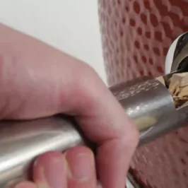 Adding wood chips into a Saffire grill using the smokin' chip feeder tube tool