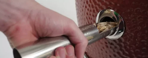 Adding wood chips into a Saffire grill using the smokin' chip feeder tube tool
