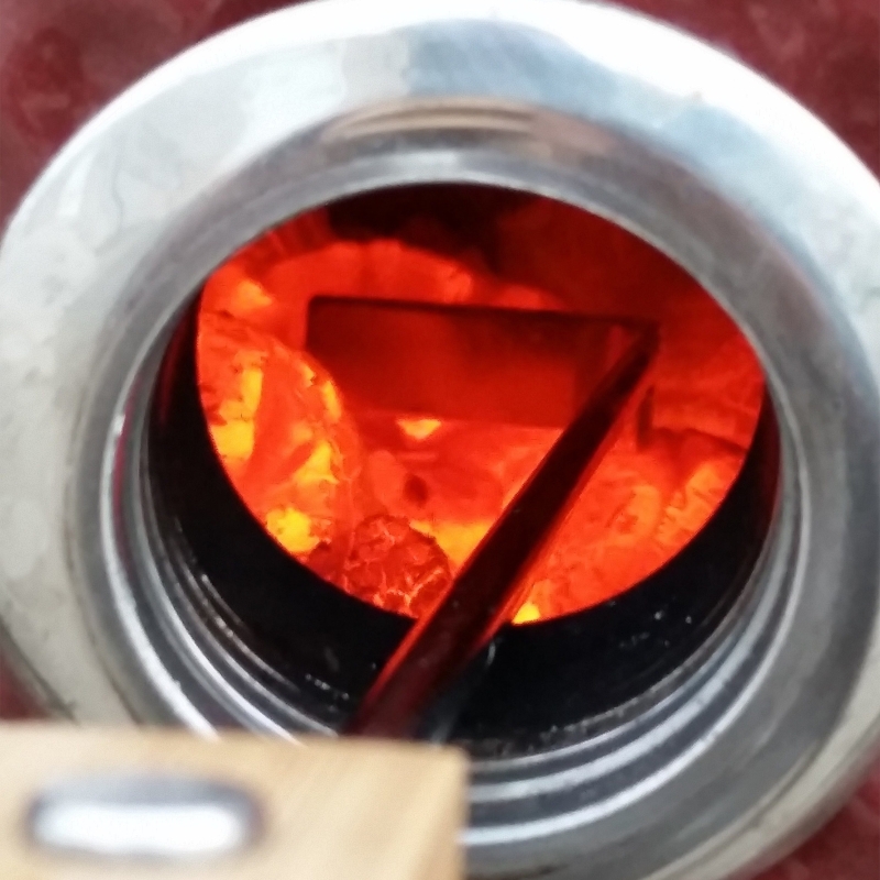 Stocking the hot charcoal with the ash cleaning tool through the smokin chip feeder port, without opening the Saffire