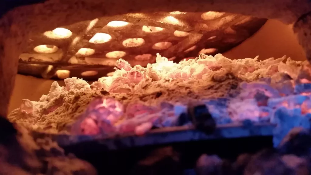 Charcoal ash shown underneath the charcoal grate, from the perspective of someone looking through the ash door of a Saffire