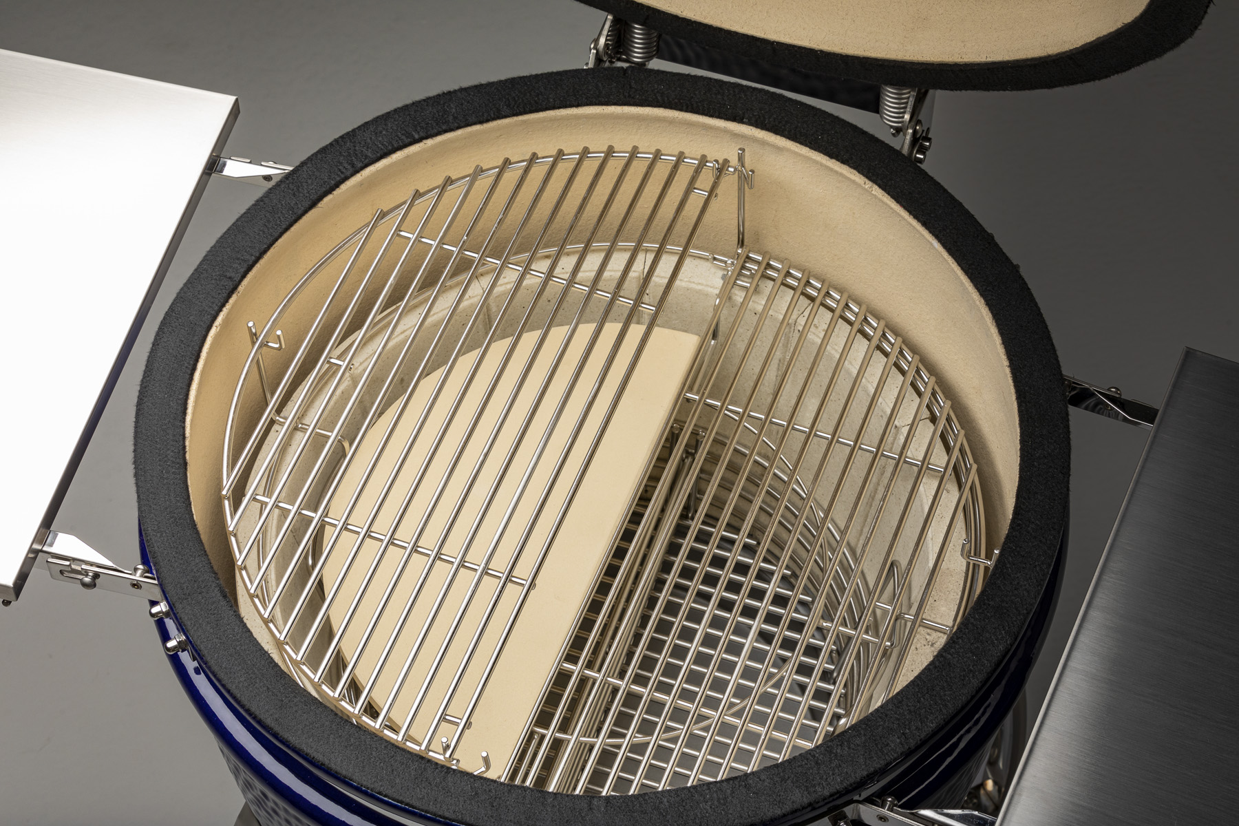 A Platinum Saffire grill is shown with the Multi-Grid, Two-Piece Ceramic Heat Deflector, Charcoal Basket and Ash Pan showing.
