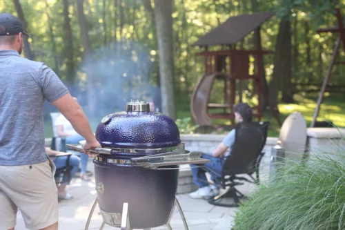 A man is grilling in his backyard on a large blue Saffire.