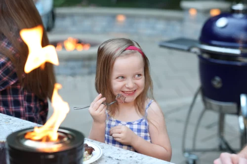 A girl sitting in front of a tabletop fire pit and smiling.