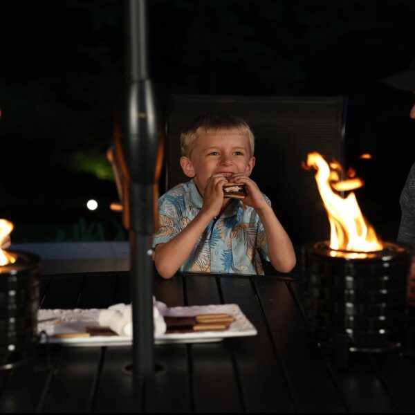 young-family-eating-smores-at-a-backyard-table-by-fire-pit