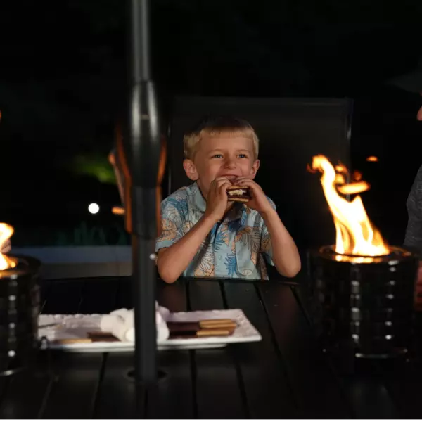 young-family-eating-smores-at-a-backyard-table-by-fire-pit